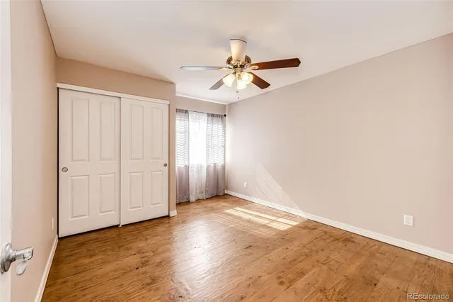 an empty room with windows and fan