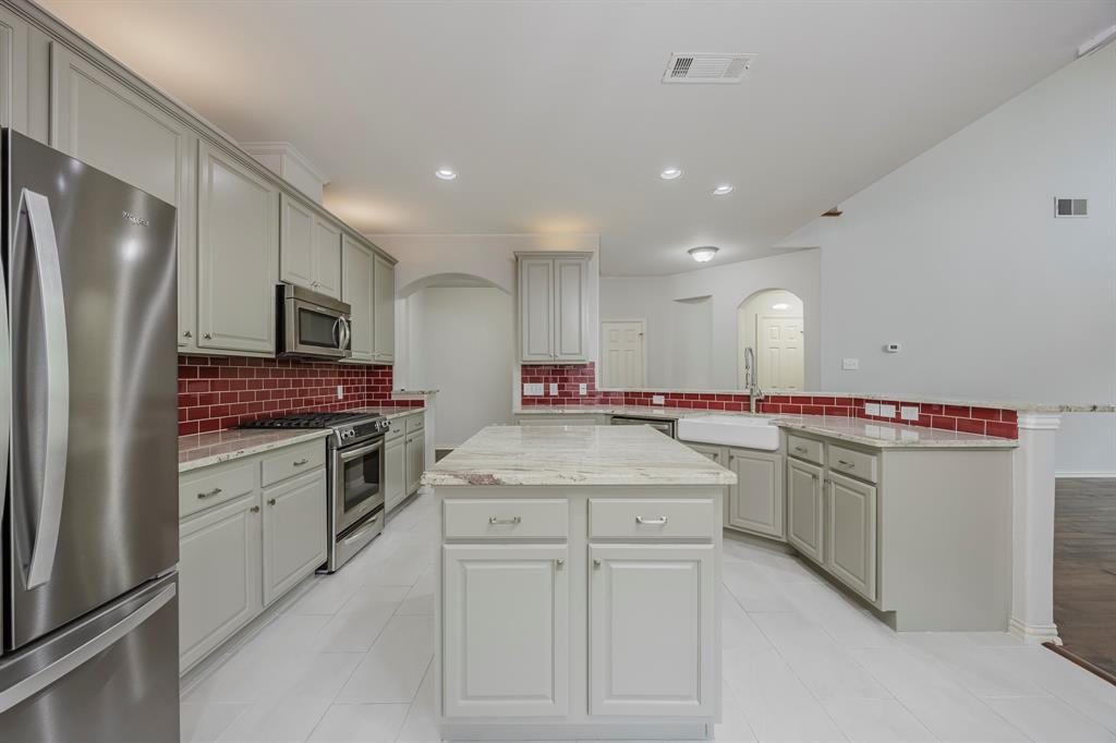 362 Spring Meadow Drive Fairview, TX 75069 - Photo 12 of 38 a kitchen with white cabinets and stainless steel appliances