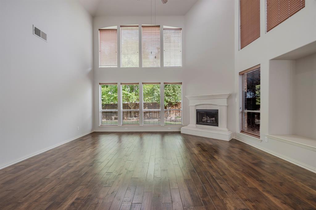 362 Spring Meadow Drive Fairview, TX 75069 - Photo 14 of 38 an empty room with wooden floor a fireplace and windows