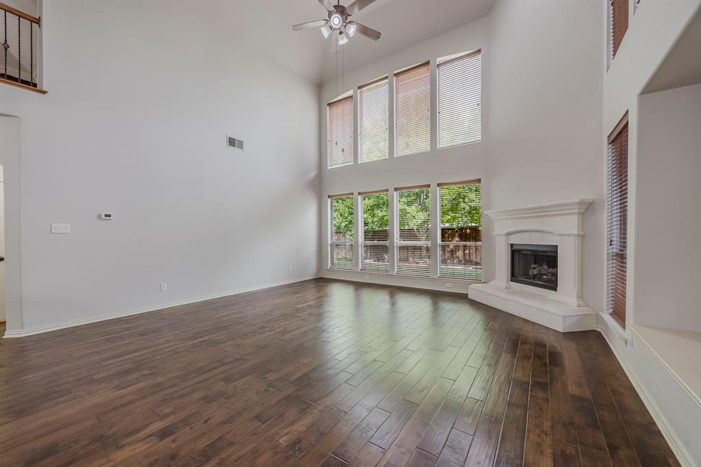 362 Spring Meadow Drive Fairview, TX 75069 - Photo 15 of 38 an empty room with wooden floor a fireplace and windows