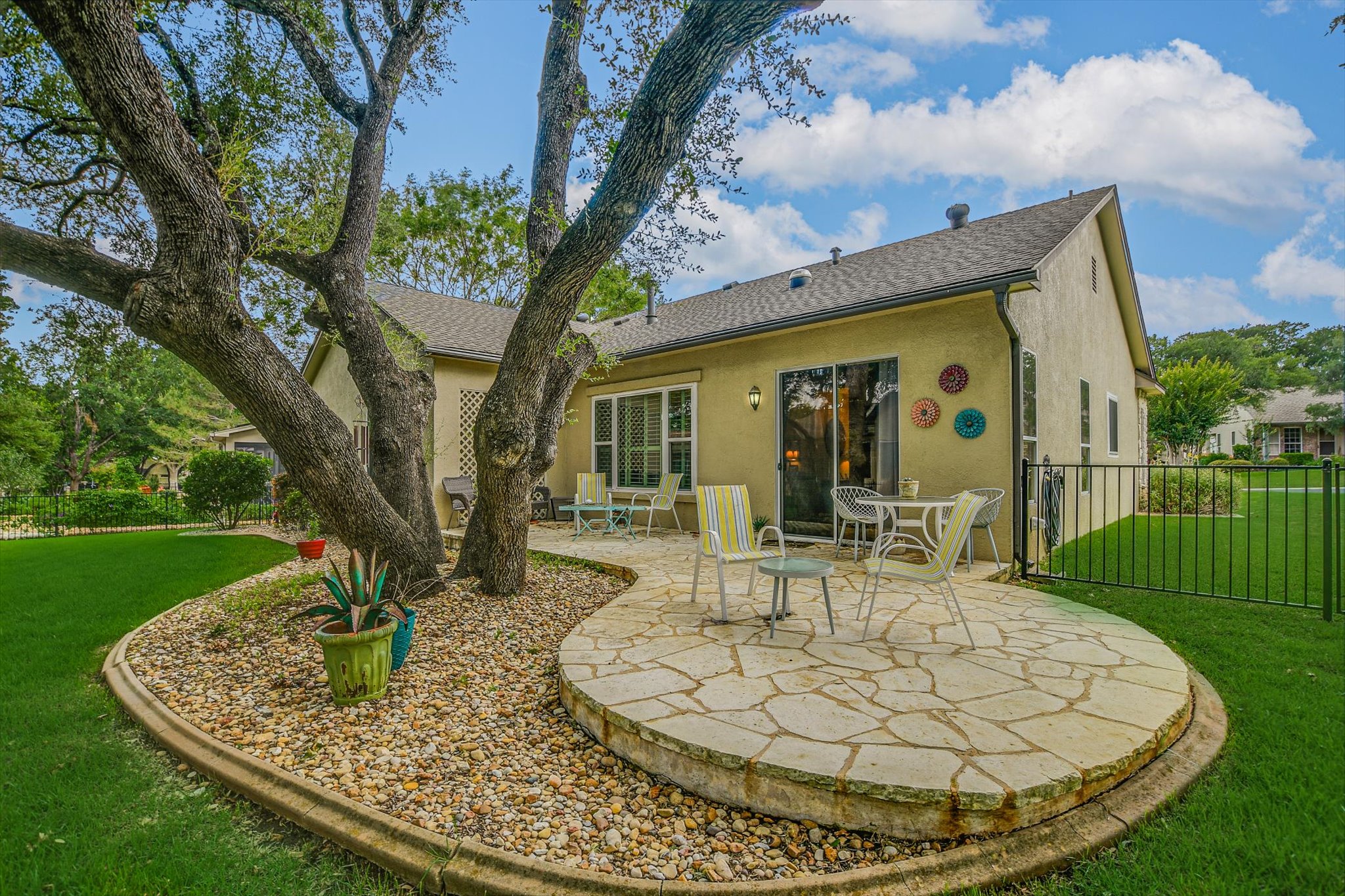 106 Nighthawk Way Georgetown, TX 78633 - Photo 23 of 29 An inviting stone patio offers a secluded outdoor living space, shaded by mature trees and surrounded by lush green lawn.