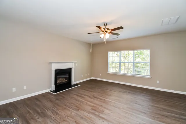 an empty room with windows fireplace and a wooden floor
