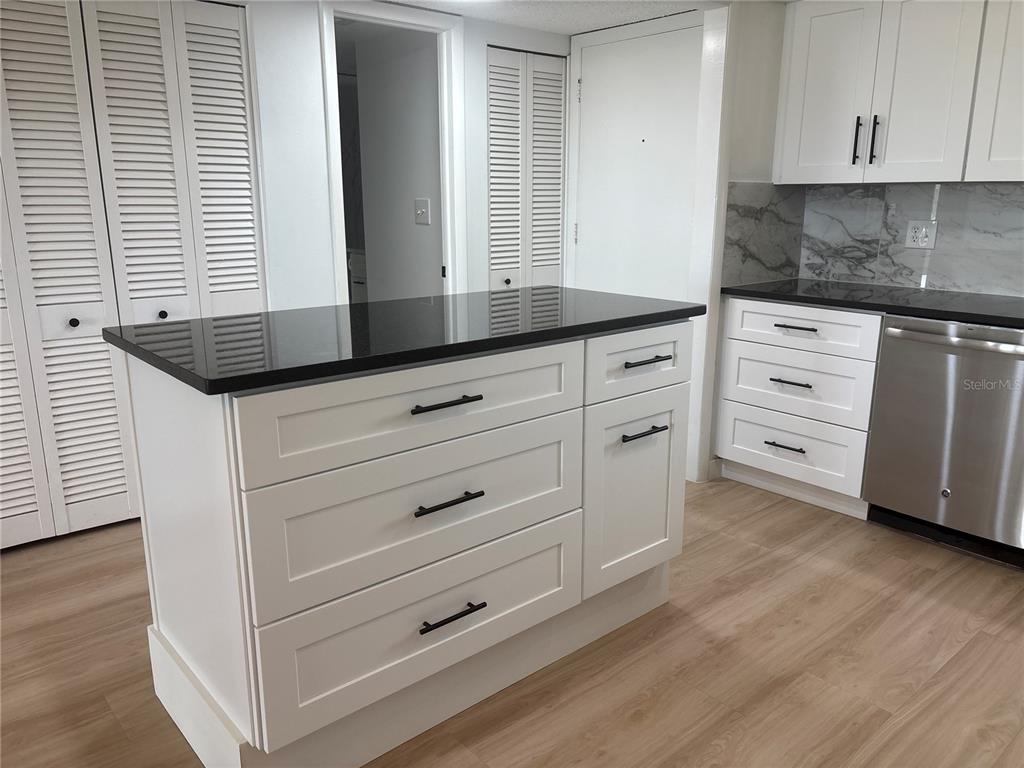 4725 Cove Circle, Unit 405 St. Petersburg, FL 33708 - Photo 6 of 23 a kitchen with granite countertop white cabinets and white appliances