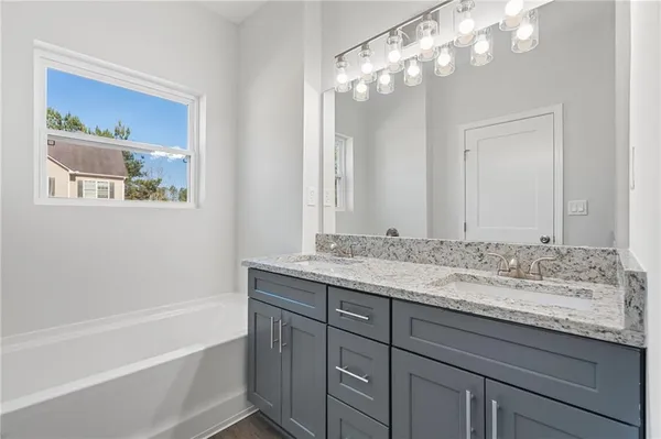 a bathroom with a granite countertop sink a large mirror and a bathtub