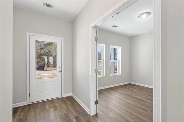 a view of an empty room with wooden floor and a window