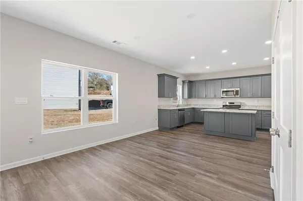 a large white kitchen with kitchen island a sink wooden floor and a living room view