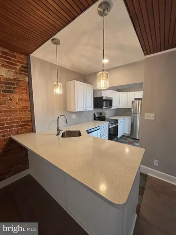 a large kitchen with stainless steel appliances a large counter top a stove and a refrigerator