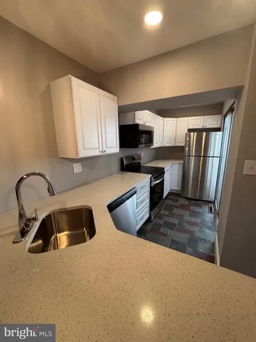 a kitchen with stainless steel appliances a stove a sink and a refrigerator