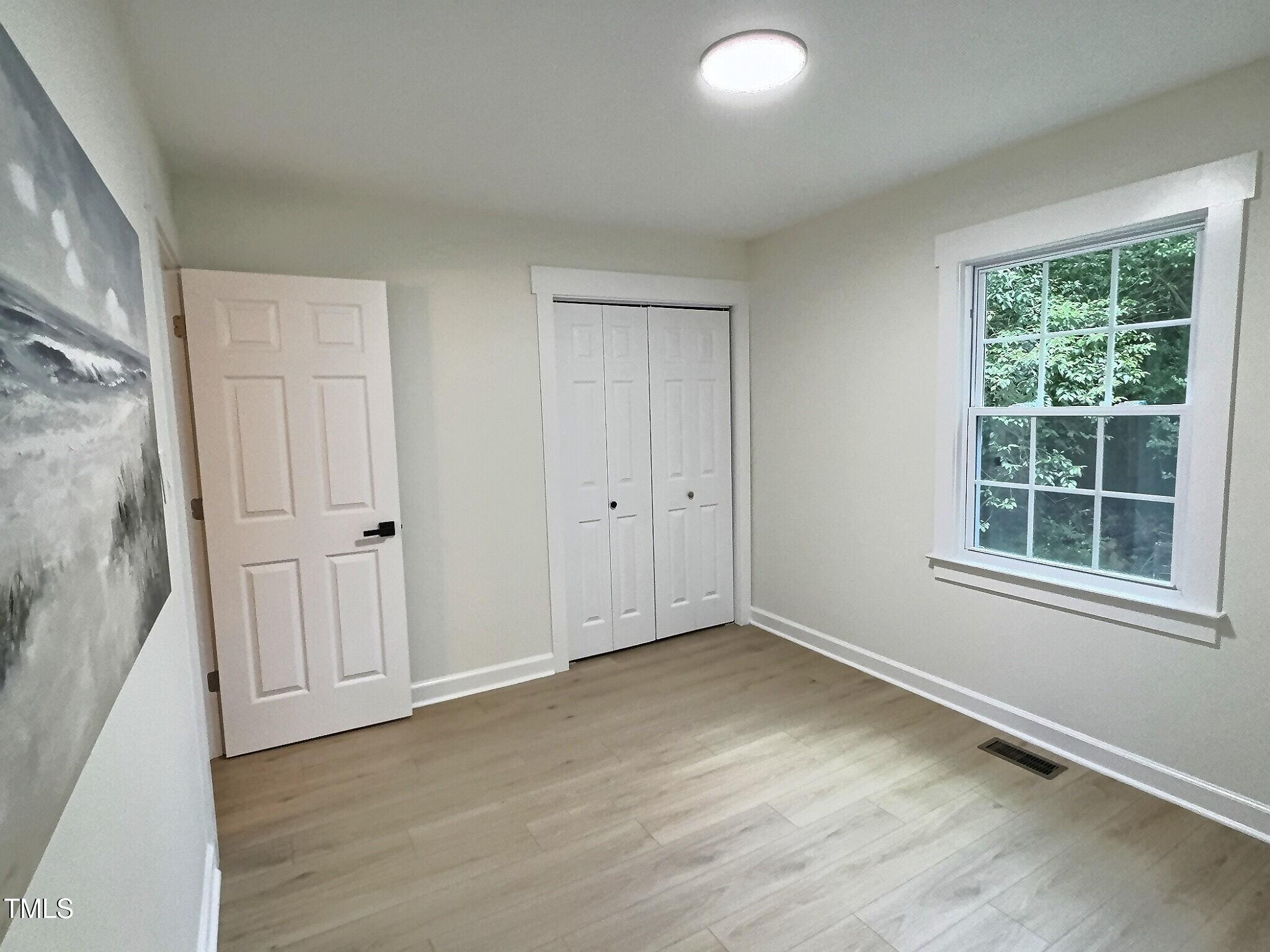 116 Lumpkin Street Raleigh, NC 27610 - Photo 14 of 20 an empty room with wooden floor and windows