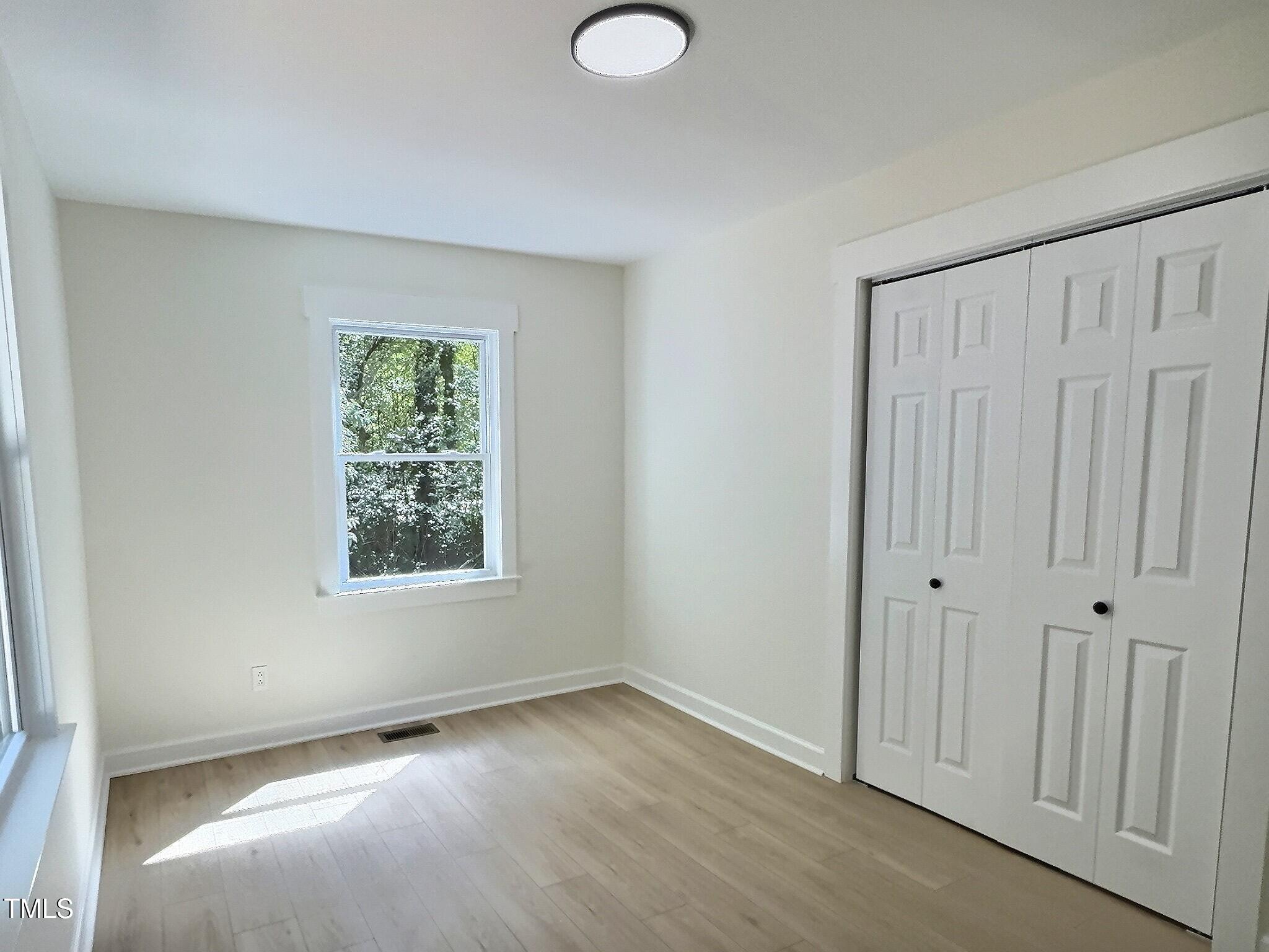 116 Lumpkin Street Raleigh, NC 27610 - Photo 17 of 20 an empty room with wooden floor and windows