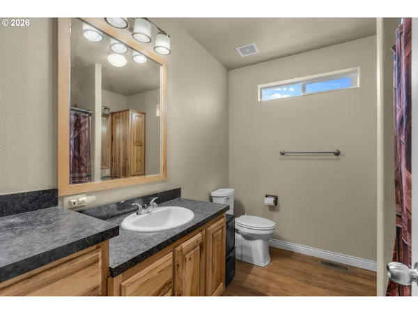a bathroom with a granite countertop sink a toilet a mirror and shower