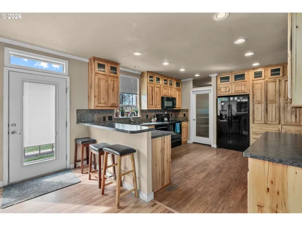a living room with stainless steel appliances kitchen island granite countertop furniture and a wooden floor