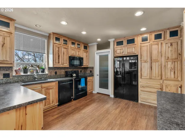 a kitchen with stainless steel appliances granite countertop a refrigerator oven a sink dishwasher and wooden cabinets with wooden floor