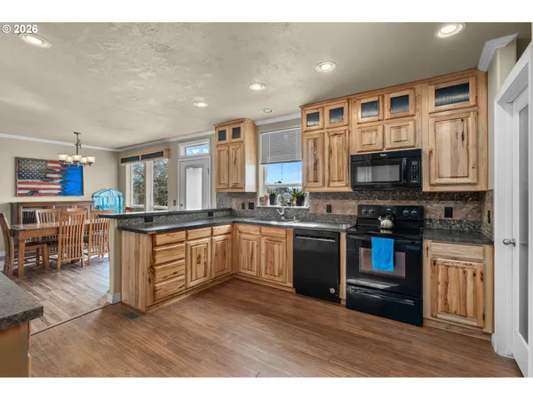 a kitchen with stainless steel appliances granite countertop a stove top oven a sink dishwasher a dining table and chairs with wooden floor