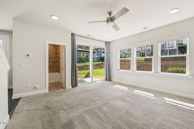 a view of an empty room with a window and a kitchen