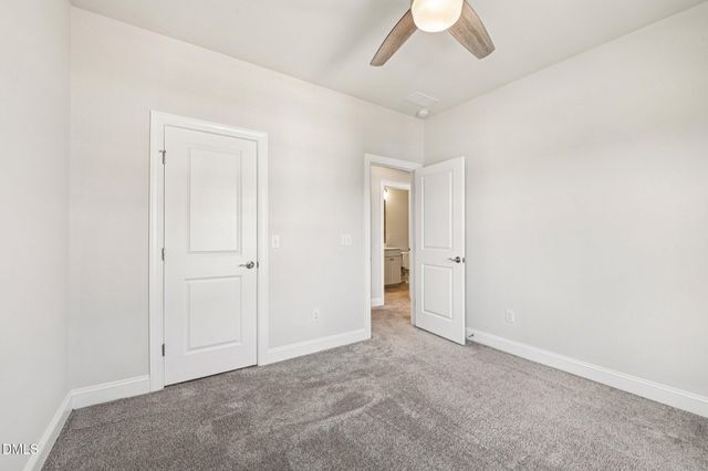an empty room with chandelier fan and windows