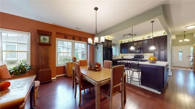 a dining room with wooden floor a chandelier a wooden table and chairs