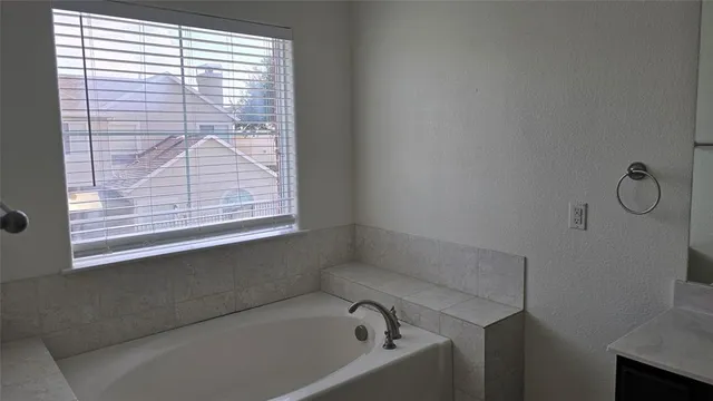a bathroom with a tub sink and mirror
