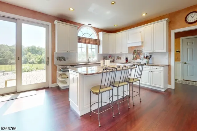 a kitchen with stainless steel appliances granite countertop a stove top oven a sink a dining table and chairs