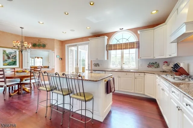a kitchen with granite countertop a stove a sink a dining table and chairs