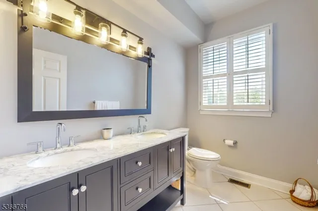 a bathroom with a granite countertop sink a toilet and a mirror