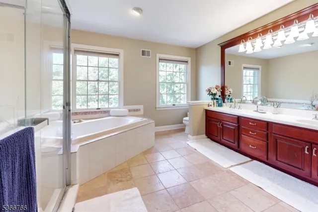 a spacious bathroom with a tub sink shower and mirror