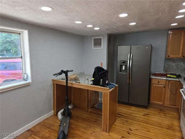 a view of a kitchen with refrigerator and wooden floor