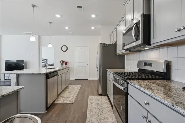 a kitchen with stainless steel appliances granite countertop a stove a sink and a microwave