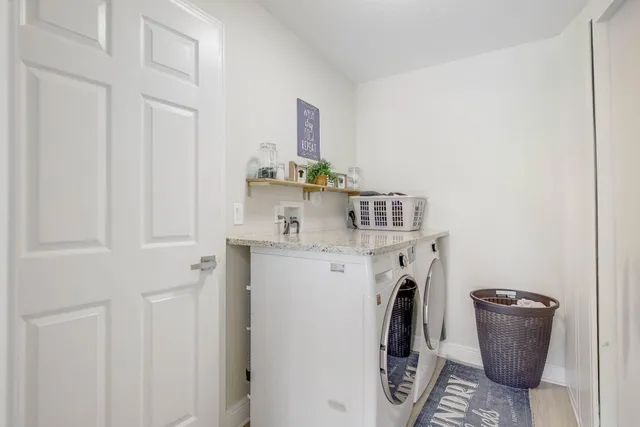 a large white kitchen with stainless steel appliances a sink a counter top space cabinets and a couch