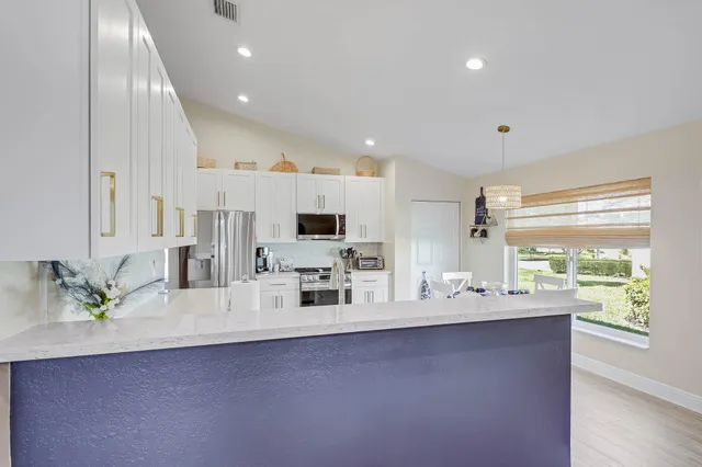 a kitchen with cabinets stainless steel appliances and wooden floor