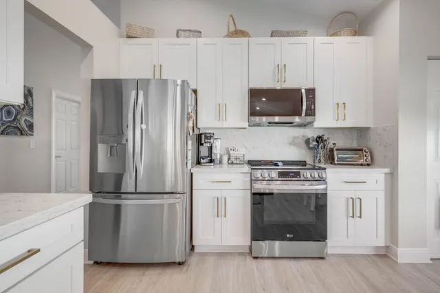 a room with stainless steel appliances kitchen island a large window and a sink