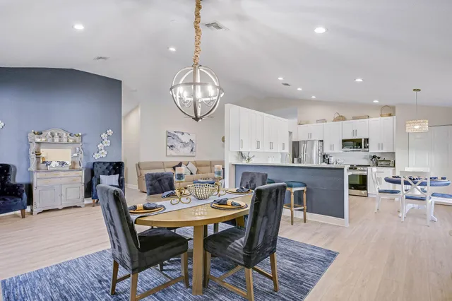 a view of a dining room and livingroom with furniture wooden floor a chandelier
