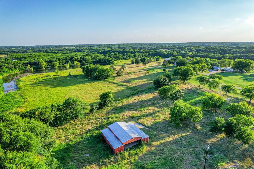 1922 A Bethel-Cannon Road Whitewright, TX 75491 - Photo 40 of 40 Expansive agricultural land featuring a red barn with a metal roof, mature trees, and a winding creek