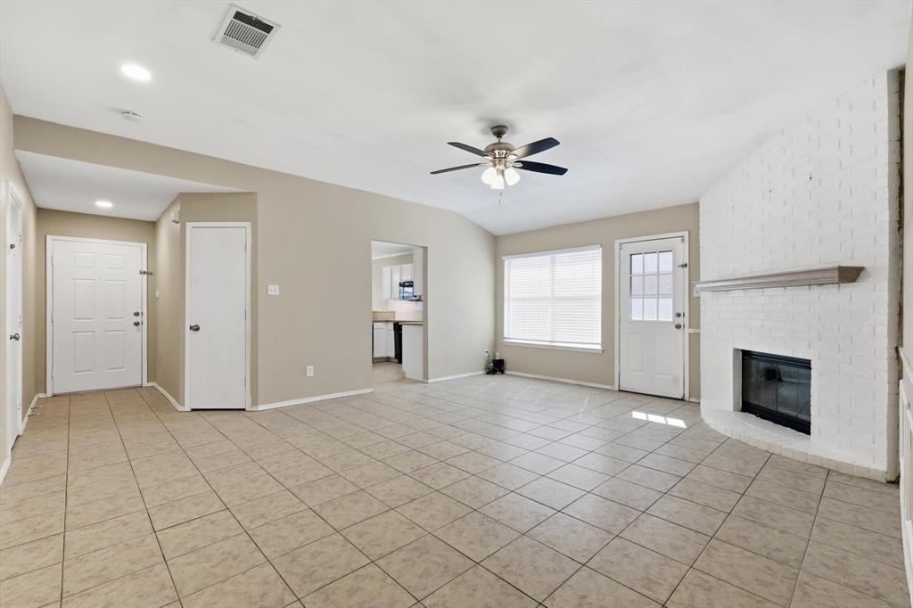 7733 Liz Lane Watauga, TX 76148 - Photo 6 of 27 Unfurnished living room featuring ceiling fan, light tile patterned flooring, and a brick fireplace