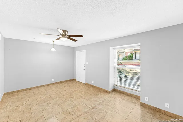 an empty room with ceiling fan and window