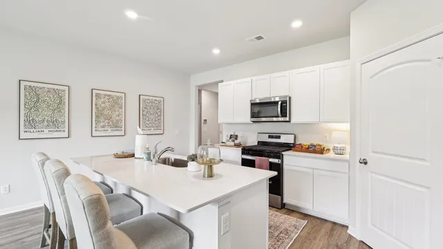 a kitchen with stainless steel appliances a stove a sink a dining table and chairs