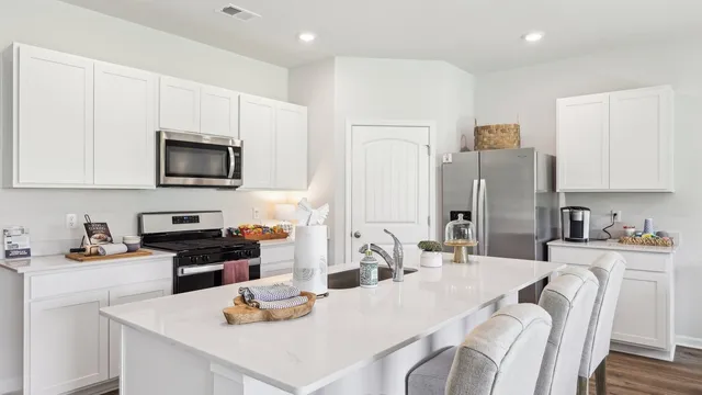 a kitchen with stainless steel appliances a dining table chairs refrigerator and sink