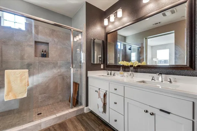 a bathroom with a double vanity sink mirror and shower