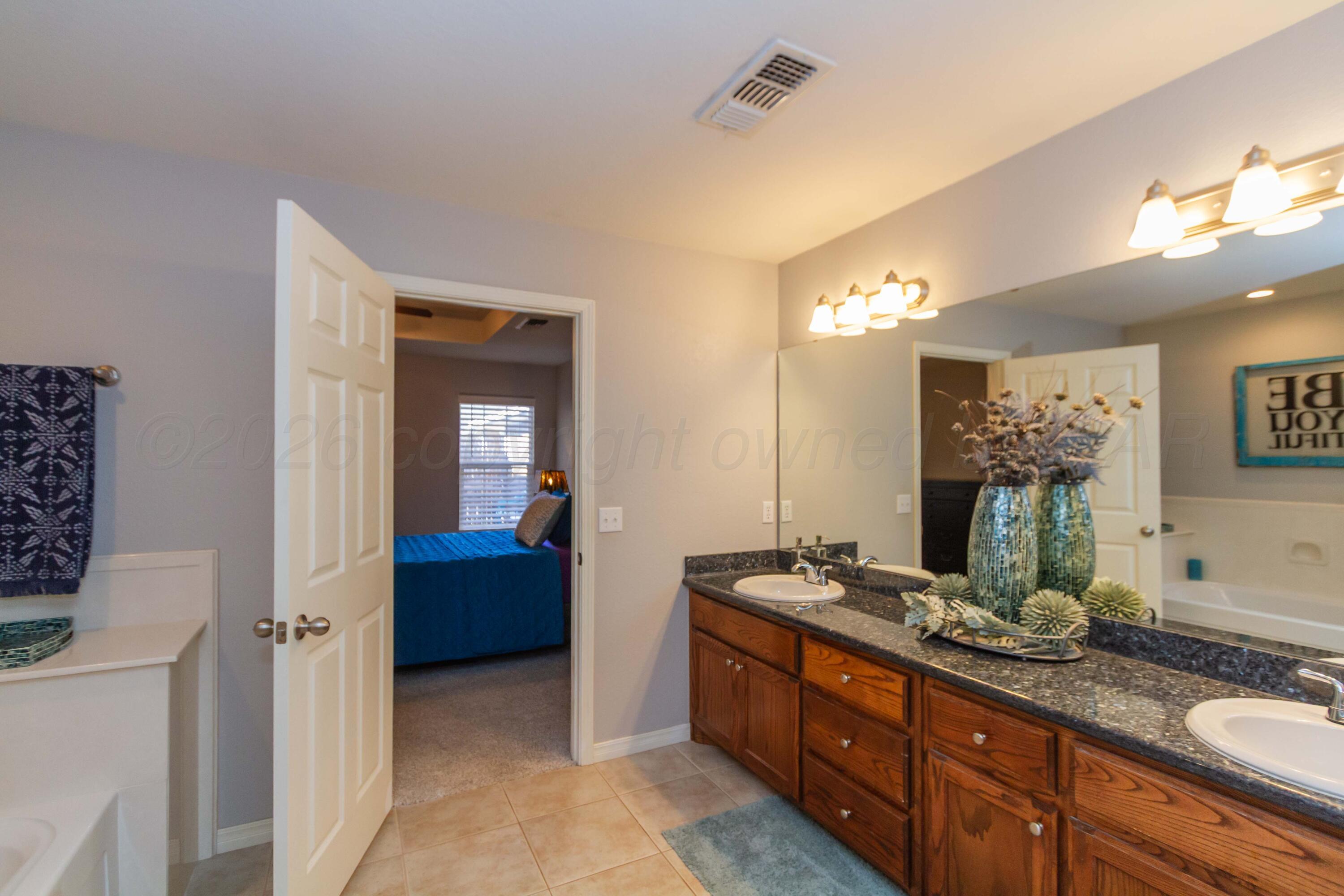 2802 Steve's Way Amarillo, TX 79118 - Photo 20 of 30 a spacious bathroom with a granite countertop sink and a mirror
