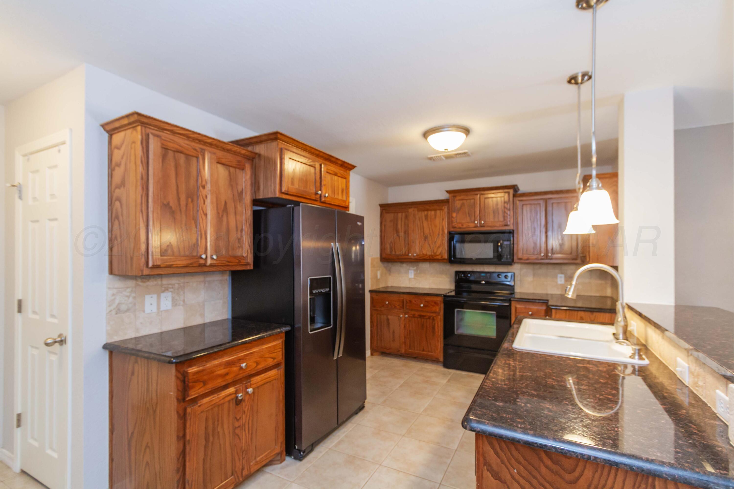 2802 Steve's Way Amarillo, TX 79118 - Photo 8 of 30 a kitchen with stainless steel appliances granite countertop a refrigerator a stove and a sink with wooden cabinets