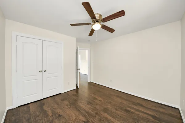 an empty room with wooden floor ceiling fan and window