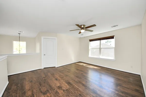 a view of empty room with wooden floor and fan