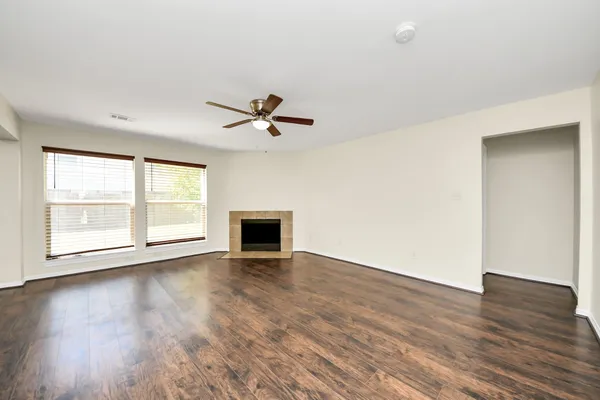 an empty room with wooden floor and windows