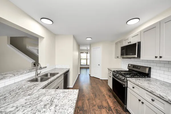 a kitchen with granite countertop a sink appliances and cabinets