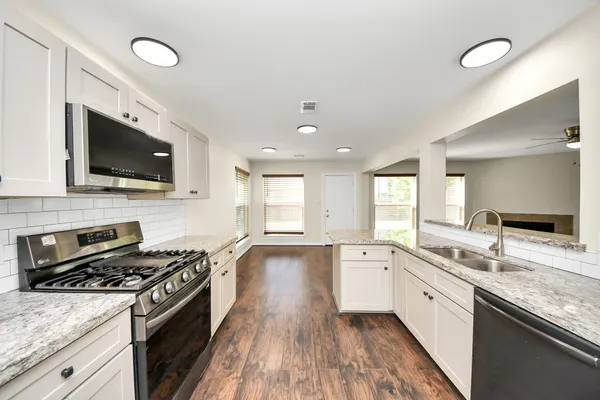 an empty room with wooden floor ceiling fan and windows