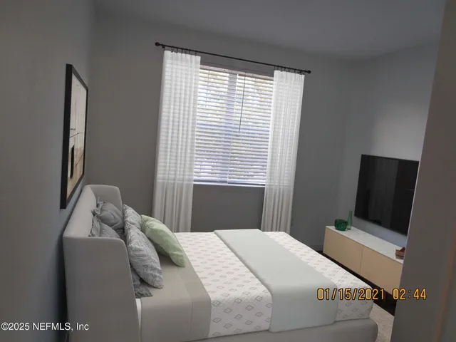 a bedroom with a bed tv and a window