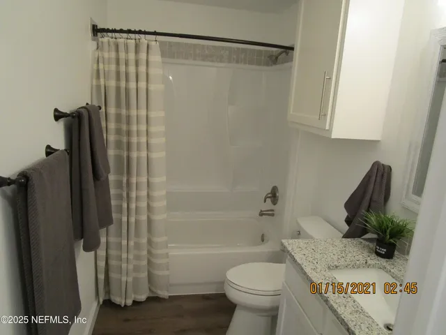 a bathroom with a granite countertop bathtub shower sink vanity and toilet