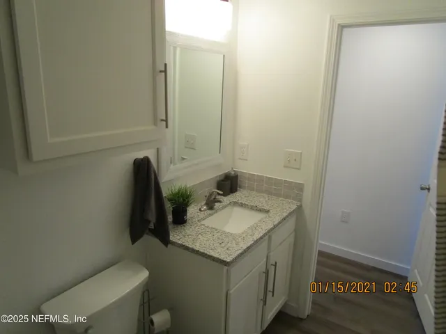 a bathroom with a granite countertop sink and a toilet