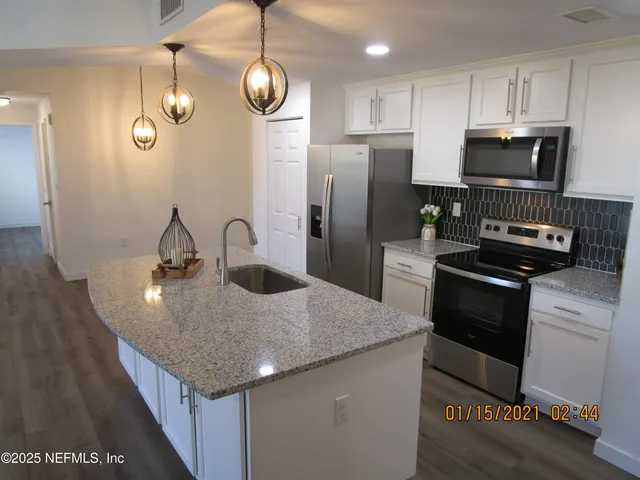 a kitchen with stainless steel appliances granite countertop a sink dishwasher a refrigerator a microwave oven with cabinets and wooden floor