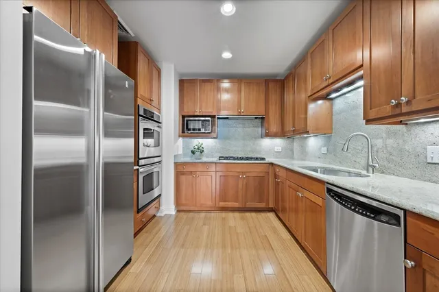 a kitchen with stainless steel appliances granite countertop a refrigerator a sink and wooden cabinets